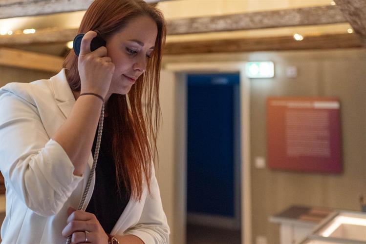 Eine Frau mit einem Einhand-Hörer an einer Audio-Station in der Ausstellung "UN#ERHÖRT, dieser Bruckner!"